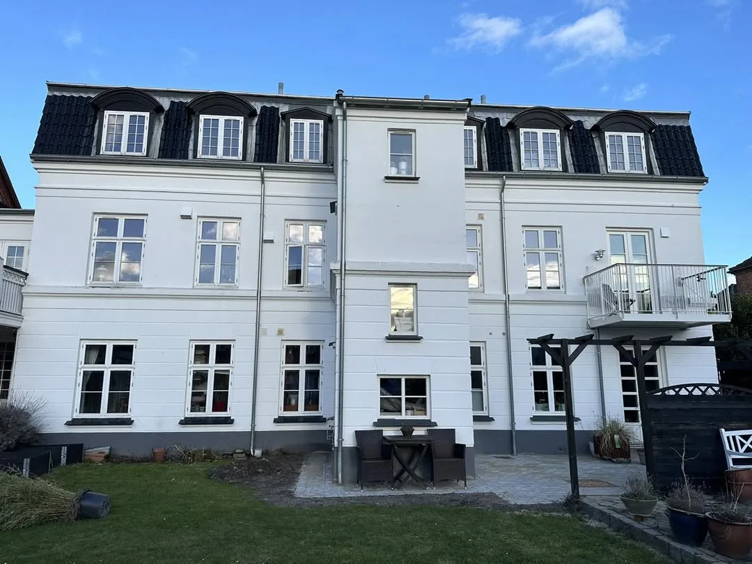 Vinduer på større hvid ejendom set fra gården